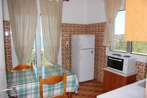 a kitchen with a table and a refrigerator and windows at Eleni Houses in Kómboi