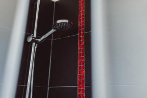 La salle de bains est pourvue d'une douche avec un pommeau de douche rouge. dans l'établissement HEIMAT | Hotel & Boarding House, à Mainburg