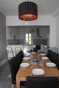 a dining room with a wooden table with plates and wine glasses at Gîte Le Margautier classé 3 étoiles proche Lamotte Beuvron in Saint-Viâtre