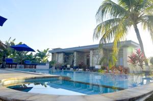 a swimming pool in front of a house with palm trees at Villa Romy and Bungalows in Lovina