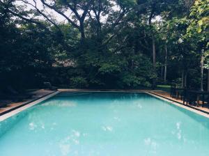a large blue swimming pool with trees in the background at Bungalow Sud in Habaraduwa Central