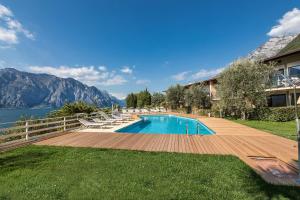 a swimming pool with chairs and a house at Residence Parco Lago di Garda in Malcesine