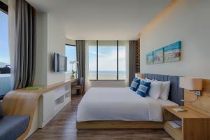 a hotel room with a bed and a large window at Belle Maison Parosand Da Nang Hotel -managed by H&K Hospitality in Da Nang