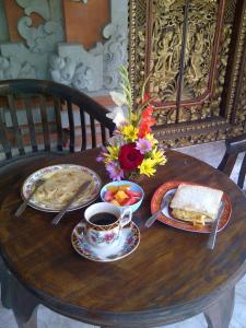 uma mesa de madeira com pratos de comida e uma chávena de café em Eka's Homestay em Ubud
