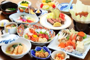 une table avec de nombreuses assiettes de nourriture dans l'établissement 吸う温泉 湯治の宿 竜王ラドン温泉 湯ーとぴあ, à Kai