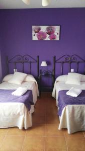 two beds in a room with purple walls at La Huerta del Rodeo in Navas de San Antonio +46 photos