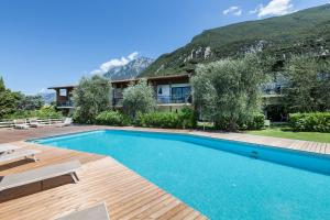 una piscina di fronte a una casa con una montagna di Residence Parco Lago di Garda a Malcesine