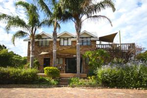 a house with palm trees in front of it at Moonriver Self Catering in Plettenberg Bay