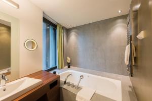 ein Badezimmer mit einer Badewanne und einem Waschbecken in der Unterkunft Belvoir Swiss Quality Hotel in Rüschlikon