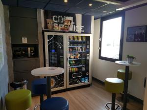 a restaurant with a refrigerator and tables and chairs at Ibis Budget Dole-Choisey in Dole