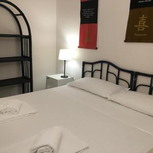 een slaapkamer met een bed met witte lakens en een lamp bij Portorosa Villa Sole in Furnari