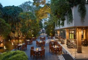 um restaurante ao ar livre com mesas, cadeiras e árvores em Cinnamon Grand Colombo em Colombo