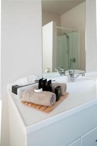 a bathroom counter with a sink with towels and a mirror at Broadway Motel & Miro Court Villas in Matamata