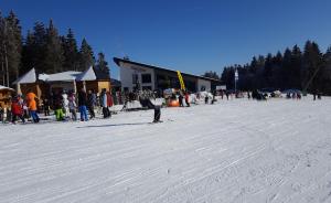 un grupo de personas de pie en la nieve frente a un edificio en Ferienhaus Bergidylle en Winterberg