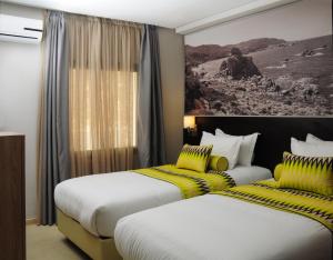 a hotel room with two beds and a painting on the wall at Appart'hotel Souani (Al Hoceima Bay) in Al Hoceïma