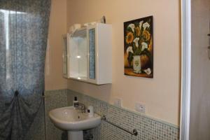 baño con lavabo y una pintura de flores en AFFITTACAMERE La Tartaruga, en Civitanova Marche