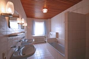 een badkamer met 2 wastafels, een bad en een tubermott bij Landhaus Zur Eiche in Sittensen