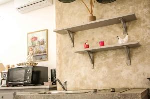 a kitchen with a tv and shelves on the wall at Le Clos du Vallon des Courances in Saint-Coutant-le-Grand