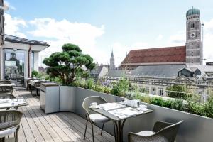 a balcony with tables and chairs and a view of the city at Hotel Bayerischer Hof in Munich