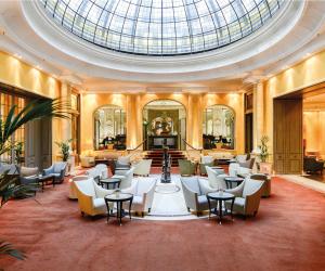 a lobby with white chairs and a skylight at Hotel Bayerischer Hof in Munich