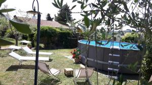 um quintal com uma piscina com cadeiras e um baloiço em Chianti Passion em Barberino di Val dʼElsa
