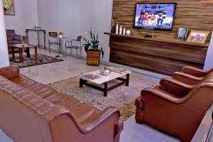 a living room with leather couches and a tv at Hotel Santa Maria in Campo Mourão