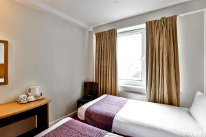 Ένα ή περισσότερα κρεβάτια σε δωμάτιο στο Ambassadors Hotel