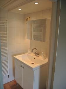 Un baño blanco con lavabo y espejo. en Ferienhaus Gapinge Walcheren Zeeland, en Veere