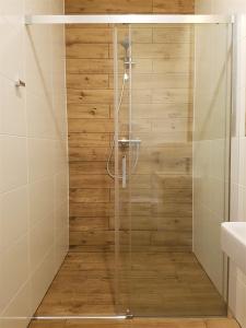 a shower with a glass door in a bathroom at 5 Zmysłów akademia wypoczynku Pokoje in Grzybowo