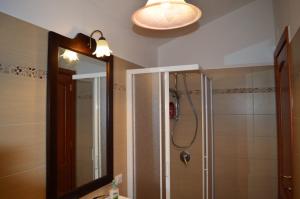 ein Bad mit einer Dusche und einem Spiegel in der Unterkunft Pineta Spiaggia Grande 2 in SantʼAntìoco