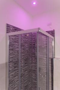 La salle de bains est pourvue d'une douche en verre et d'un éclairage violet. dans l'établissement 4Rooms Milano, à Milan