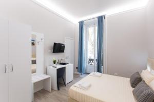 Cette petite chambre blanche comprend un lit et un bureau. dans l'établissement 4Rooms Milano, à Milan