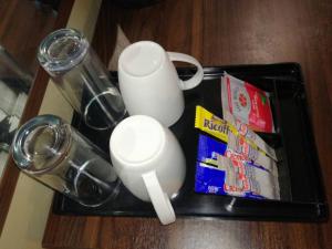 un vassoio con tazze e bevande e una borsa di patatine di La Signature Guest house a Francistown