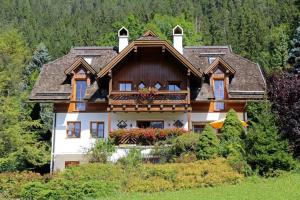 a house on top of a hill with trees at Landhaus Sonneck in Weissensee