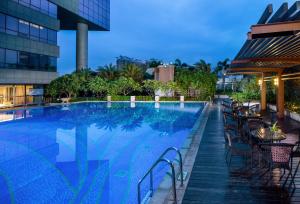 a swimming pool with tables and chairs next to a building at Sentosa Hotel Shenzhen Feicui Branch, Enjoy tropical swimming pools and high-class fitness club in Shenzhen