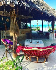 a beach with a hut and chairs and the ocean at Zanzistar Lodge in Jambiani