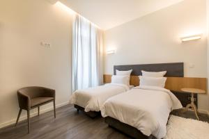 a hotel room with a bed, chair, and nightstand at LETHESHOME Apartments in Porto