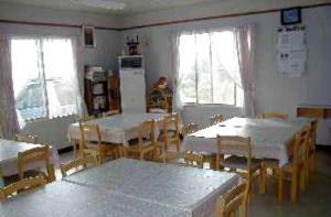 a dining room with tables and chairs and windows at Abashiri Ryuhyou no Oka guesthouse in Abashiri
