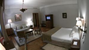 a hotel room with a bed and a living room at Parador de Santiago - Hostal Reis Catolicos in Santiago de Compostela