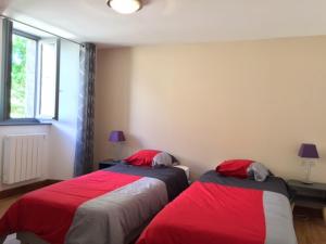 two beds in a room with red and gray at La Grange du Lac de Cantalès in Lacapelle-Viescamp