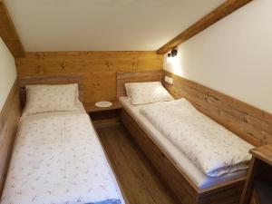 two beds in a small room with wooden walls at Hoamalm in Grossarl