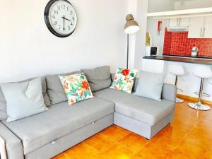 uma sala de estar com um sofá e um relógio na parede em Club Olympus in Garden City em Playa de las Americas