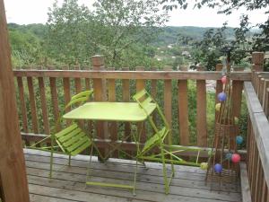Saint-Antoine-de-BreuilhにあるNuits perchées à Laroqueのデッキ(緑の椅子、テーブル付)