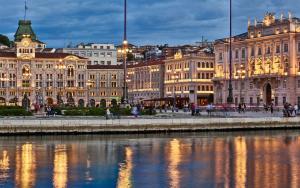 a group of buildings next to a river at night at Grand Hotel Duchi d'Aosta in Trieste