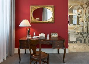 a desk with a lamp and a mirror on a red wall at Grand Hotel Duchi d'Aosta in Trieste