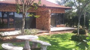 a patio with a table and two benches in a yard at Longmere Cottages in White River