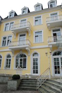 una casa amarilla con escaleras delante en Milbor Hotel, en Bad Soden am Taunus