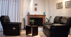 a living room with two leather chairs and a fireplace at Aigiali Rooms in Volissos