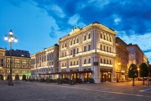 a large white building on a street at night at Grand Hotel Duchi d'Aosta in Trieste