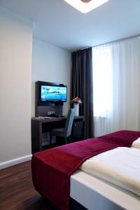 a bedroom with a bed and a desk with a television at Milbor Hotel in Bad Soden am Taunus